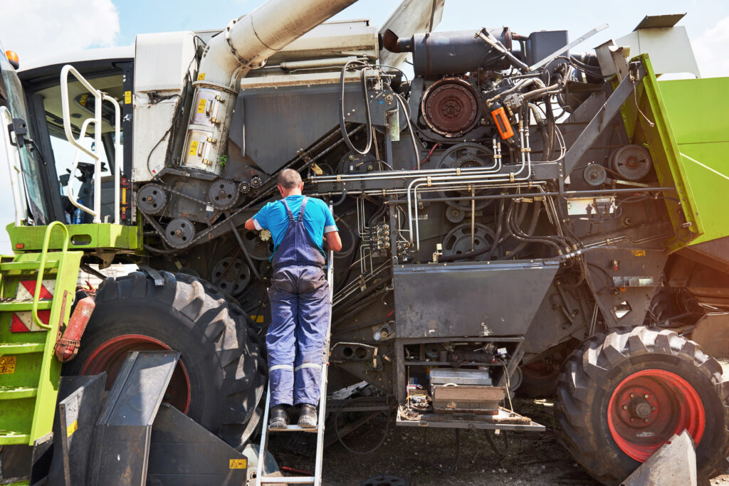 combine machine service, mechanic repairing motor outdoors combine machine service, mechanic repairing motor outdoors